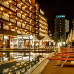 Hotel Gladiola Star nocą, z basenem, leżakami i kasynem w tle.