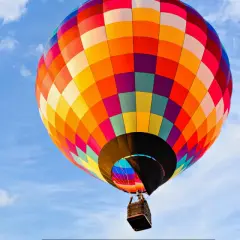 Kolorowy balon unosi się na błękitnym niebie, oferując niezapomniany lot balonem Poznań.