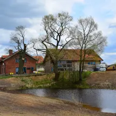 Idealne miejsce, gdzie na weekend we dwoje: urokliwe domki z cegły i drewna nad stawem, otoczone drzewami.