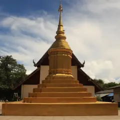 Złota pagoda, symbol buddyzmu, wznosi się na tle błękitnego nieba. Obok stoi złoty słoń.