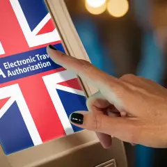 Dłoń dotyka ekranu z flagą Wielkiej Brytanii i napisem ETA. Czy Polacy potrzebują wizy do Wielkiej Brytanii? ETA to elektroniczne zezwolenie na podróż.