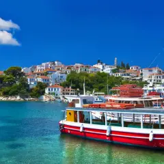 Skopelos wakacje: białe domy na wzgórzu, turkusowa woda i łodzie w porcie. Idealne miejsce na greckie wakacje.