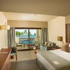 Pokój w hotelu Fanar & Residences z widokiem na basen i morze. Wygodne łóżko, sofa i balkon zapraszają do relaksu.