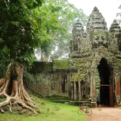 Wspaniałe kamienne twarze Angkor Thom witają na kambodżańskie wakacje. Potężne korzenie drzew oplatają starożytne mury.