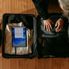 Pakowanie walizki. Zastanawiasz się, czy w bagażu rejestrowanym można mieć płyny? W środku ubrania, buty i tablet z instrukcjami.