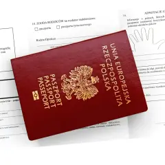 Czerwony paszport Rzeczypospolitej Polskiej leży na formularzu wniosku. Możliwość złożenia wniosku o paszport online ułatwia ten proces.