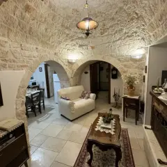 Wnętrze domków trulli z kamiennymi sklepieniami, kanapą, stolikiem kawowym i kominkiem.