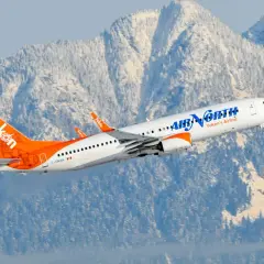 Samolot Boeing 737 linii Air North wzbija się na tle ośnieżonych gór.