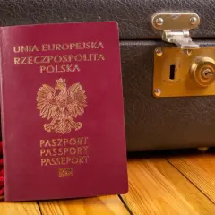 Czerwony paszport RP obok starej walizki. Gotowy na podróż do Czarnogóry? Paszport czy dowód osobisty - co zabierasz?