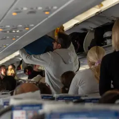 Pasażerowie w samolocie, przygotowujący bagaż podręczny. Wszyscy czekają na odlot, to typowa scena na lotnisku tranzytowym.