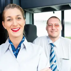 Uśmiechnięta stewardessa i kierowca autobusu, gotowi na podróż. Nasz rezydent zadba o Twój komfort.