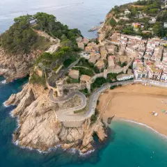 Malownicze widoki na Costa Brava wakacje: miasteczko z zamkiem na klifie, kręta droga i piaszczysta plaża.