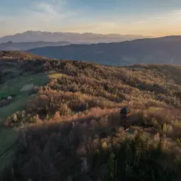 Wieża widokowa na tle zachodzącego słońca w Beskidzie Sądeckim. W oddali majaczą Tatry.