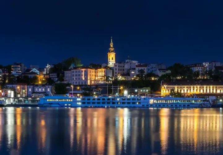 Nocny Belgrad z rzeką i statkiem wycieczkowym. Czy do Serbii potrzebny jest paszport? Sprawdź przed podróżą!