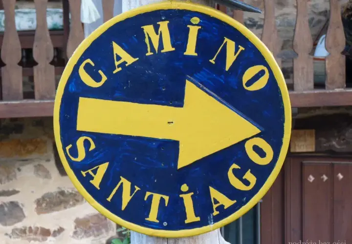 Żółta strzałka na niebieskim tle, z napisem "Camino Santiago", wskazuje drogę na szlak św. Jakuba.