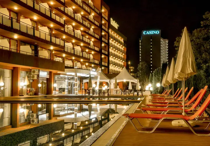 Hotel Gladiola Star nocą, z basenem, leżakami i kasynem w tle.