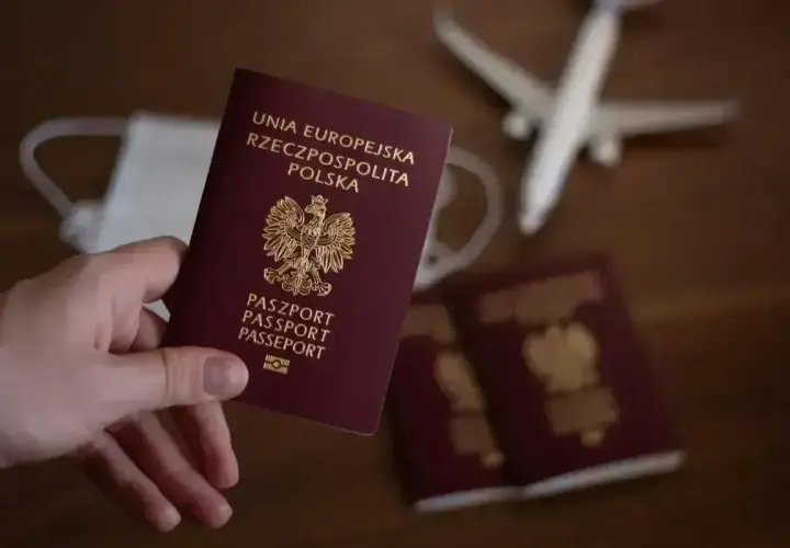 Dłoń trzyma polski paszport. Obok leżą kolejne dokumenty, maseczka i samolot. Czy do Anglii potrzebny jest paszport? Tak, jest niezbędny.