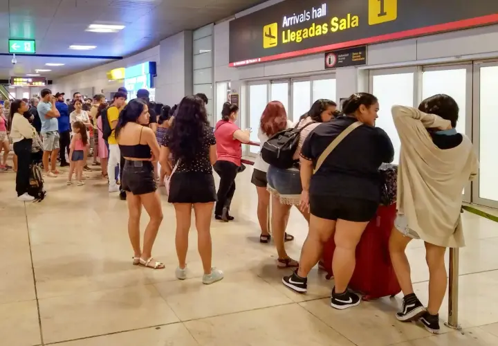 Kolejka podróżnych na lotnisku w Hiszpanii, przy tablicy "Arrivals hall Llegadas Sala 1".