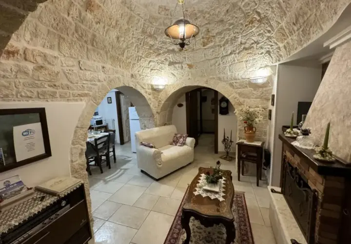 Wnętrze domków trulli z kamiennymi sklepieniami, kanapą, stolikiem kawowym i kominkiem.