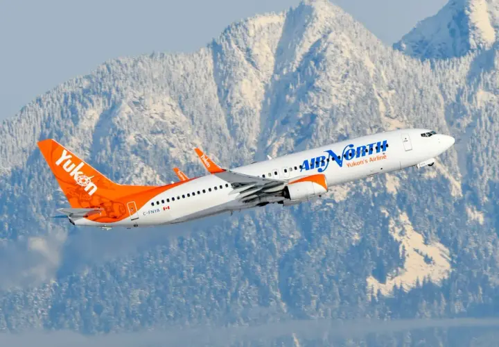 Samolot Boeing 737 linii Air North wzbija się na tle ośnieżonych gór.