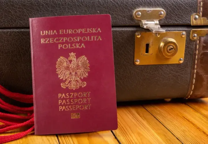 Czerwony paszport RP obok starej walizki. Gotowy na podróż do Czarnogóry? Paszport czy dowód osobisty - co zabierasz?