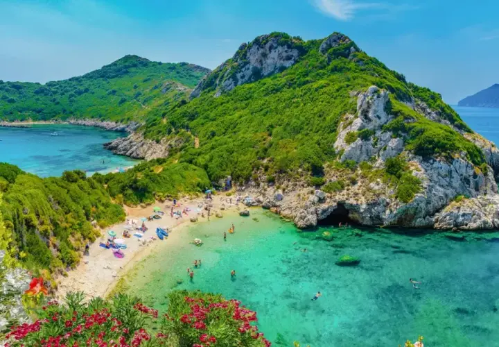Malownicza zatoka z turkusową wodą, piaszczystą plażą i zielonymi wzgórzami. Idealne miejsce na wakacje na jednych z najpiękniejszych wysp w Europie.