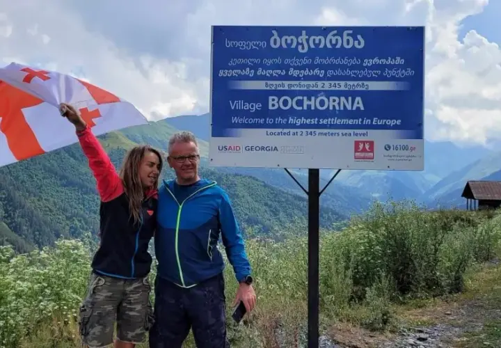 Para podróżników z flagą Gruzji w Bochorna, najwyżej położonej osadzie w Europie. Odpowiedź na pytanie: czy w Gruzji jest bezpiecznie? Tak!