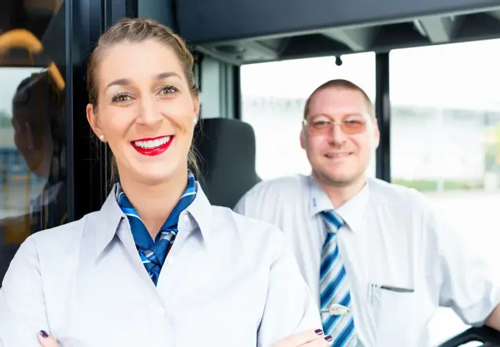 Uśmiechnięta stewardessa i kierowca autobusu, gotowi na podróż. Nasz rezydent zadba o Twój komfort.