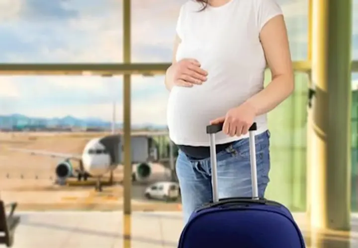 Ciężarna kobieta z walizką na lotnisku, zastanawia się, czy w ciąży można latać samolotem.