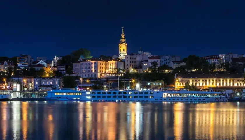 Nocny Belgrad z rzeką i statkiem wycieczkowym. Czy do Serbii potrzebny jest paszport? Sprawdź przed podróżą!