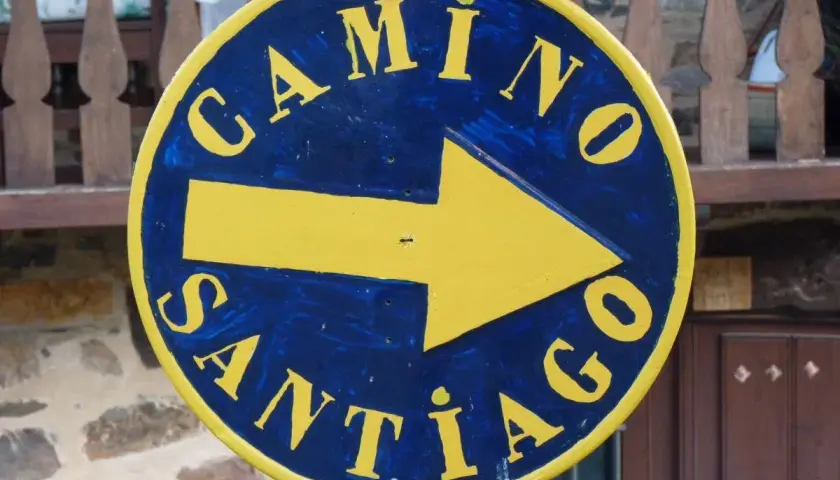 Żółta strzałka na niebieskim tle, z napisem "Camino Santiago", wskazuje drogę na szlak św. Jakuba.