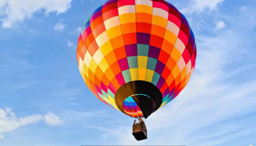Kolorowy balon unosi się na błękitnym niebie, oferując niezapomniany lot balonem Poznań.