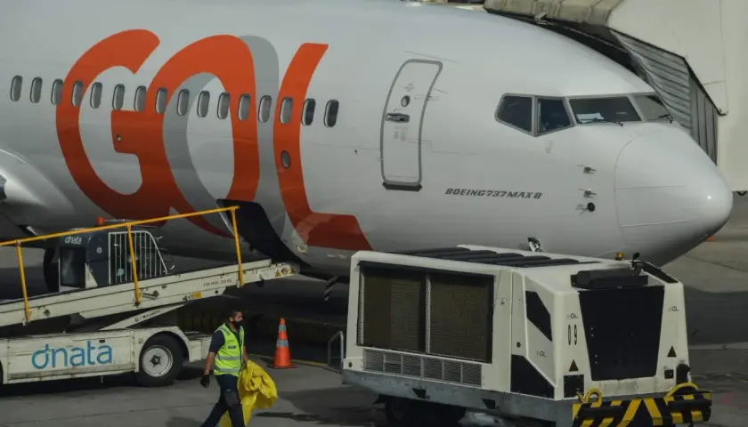 Samolot Boeing 737 MAX 8 linii GOL na lotnisku. Pracownik obsługi naziemnej niesie żółty worek.