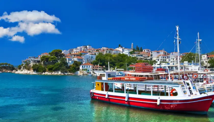 Skopelos wakacje: białe domy na wzgórzu, turkusowa woda i łodzie w porcie. Idealne miejsce na greckie wakacje.
