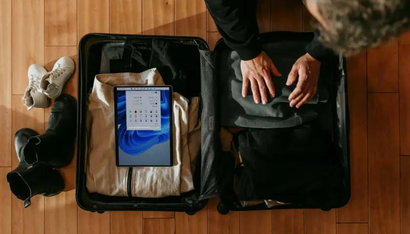 Pakowanie walizki. Zastanawiasz się, czy w bagażu rejestrowanym można mieć płyny? W środku ubrania, buty i tablet z instrukcjami.