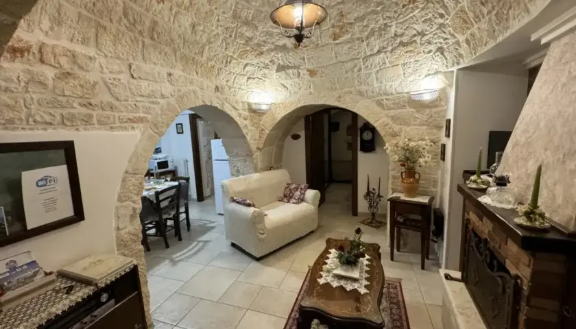 Wnętrze domków trulli z kamiennymi sklepieniami, kanapą, stolikiem kawowym i kominkiem.