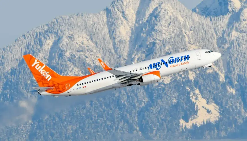Samolot Boeing 737 linii Air North wzbija się na tle ośnieżonych gór.