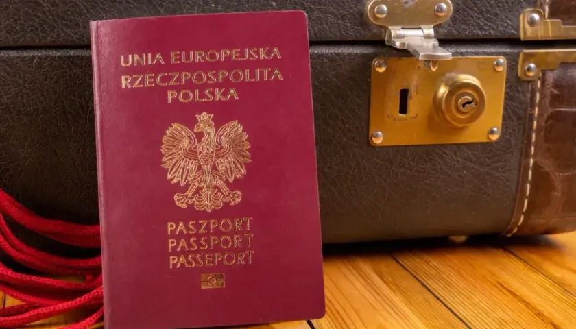 Czerwony paszport RP obok starej walizki. Gotowy na podróż do Czarnogóry? Paszport czy dowód osobisty - co zabierasz?