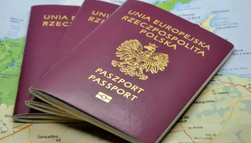 Trzy polskie paszporty leżą na mapie. Zastanawiasz się, ile się czeka na paszport, by wyruszyć w podróż?