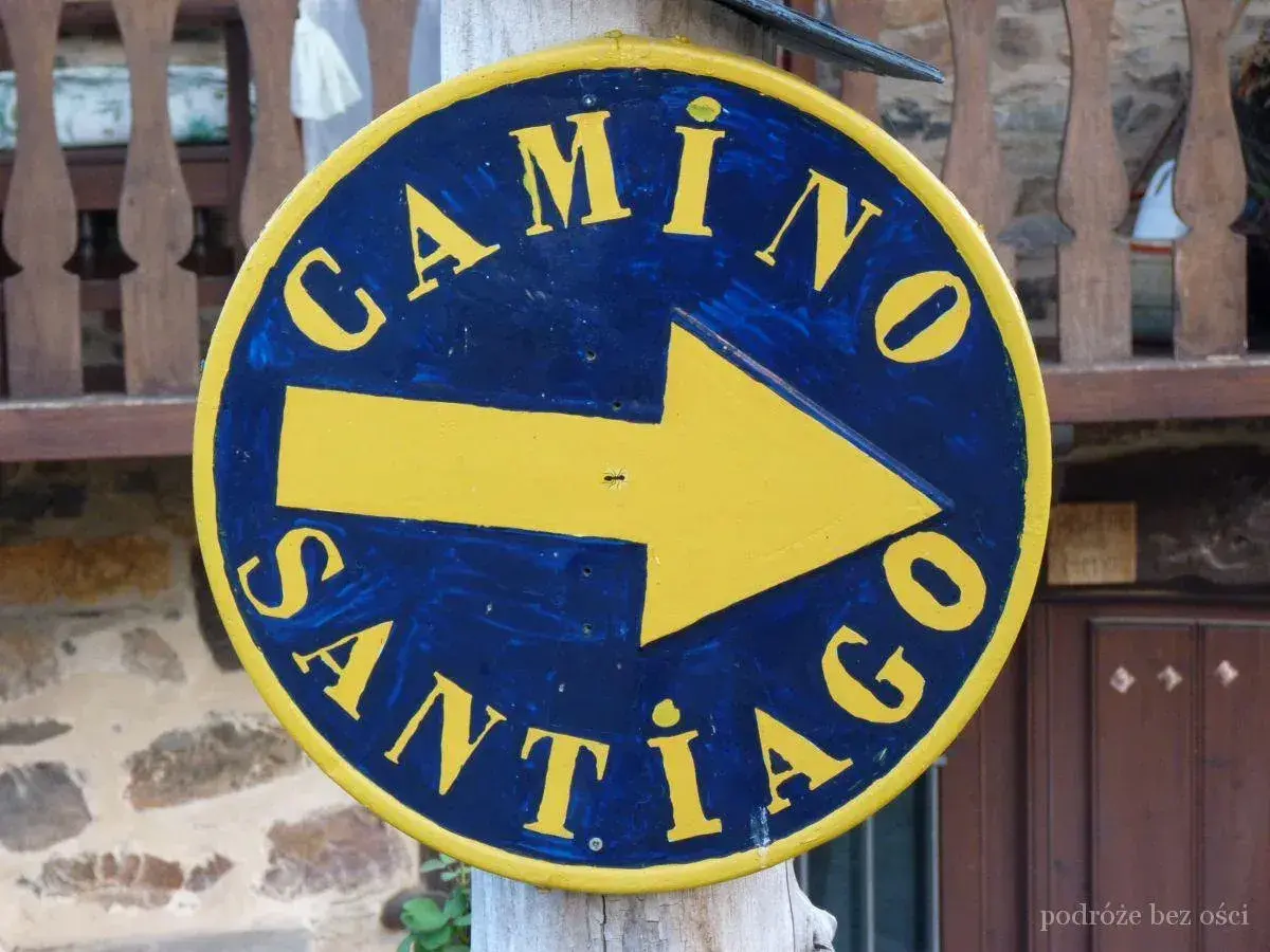 Żółta strzałka na niebieskim tle, z napisem "Camino Santiago", wskazuje drogę na szlak św. Jakuba.
