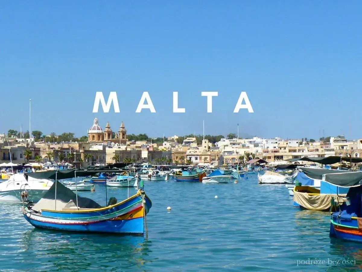 Kolorowe łodzie rybackie w porcie, z miastem i kościołem w tle. Malta historia wita żeglarzy.