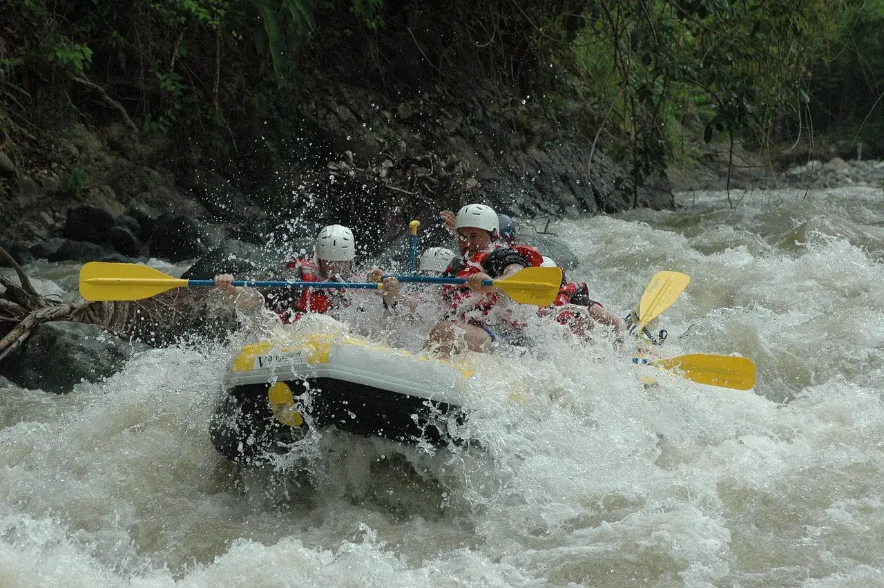 Ludzie na pontonie walczą z rwącym nurtem rzeki. To jest właśnie rafting – emocjonująca przygoda na wodzie!