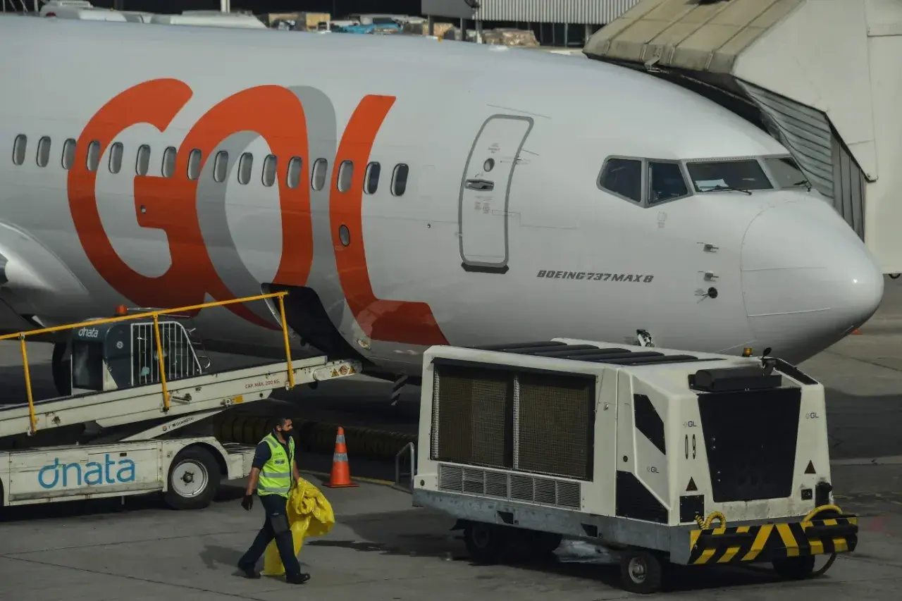 Samolot Boeing 737 MAX 8 linii GOL na lotnisku. Pracownik obsługi naziemnej niesie żółty worek.