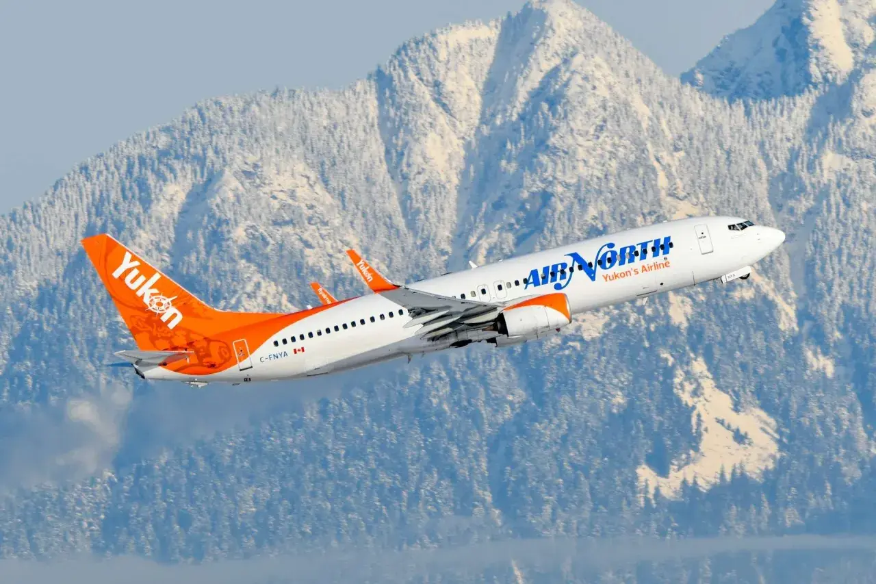 Samolot Boeing 737 linii Air North wzbija się na tle ośnieżonych gór.
