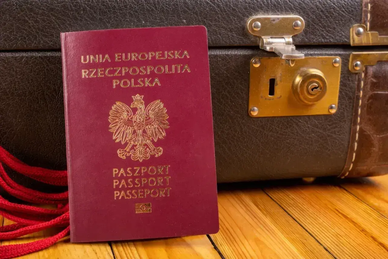 Czerwony paszport RP obok starej walizki. Gotowy na podróż do Czarnogóry? Paszport czy dowód osobisty - co zabierasz?
