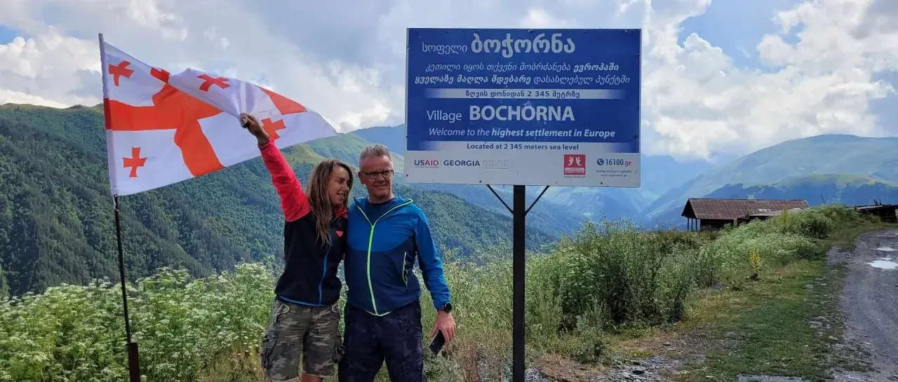 Para podróżników z flagą Gruzji w Bochorna, najwyżej położonej osadzie w Europie. Odpowiedź na pytanie: czy w Gruzji jest bezpiecznie? Tak!