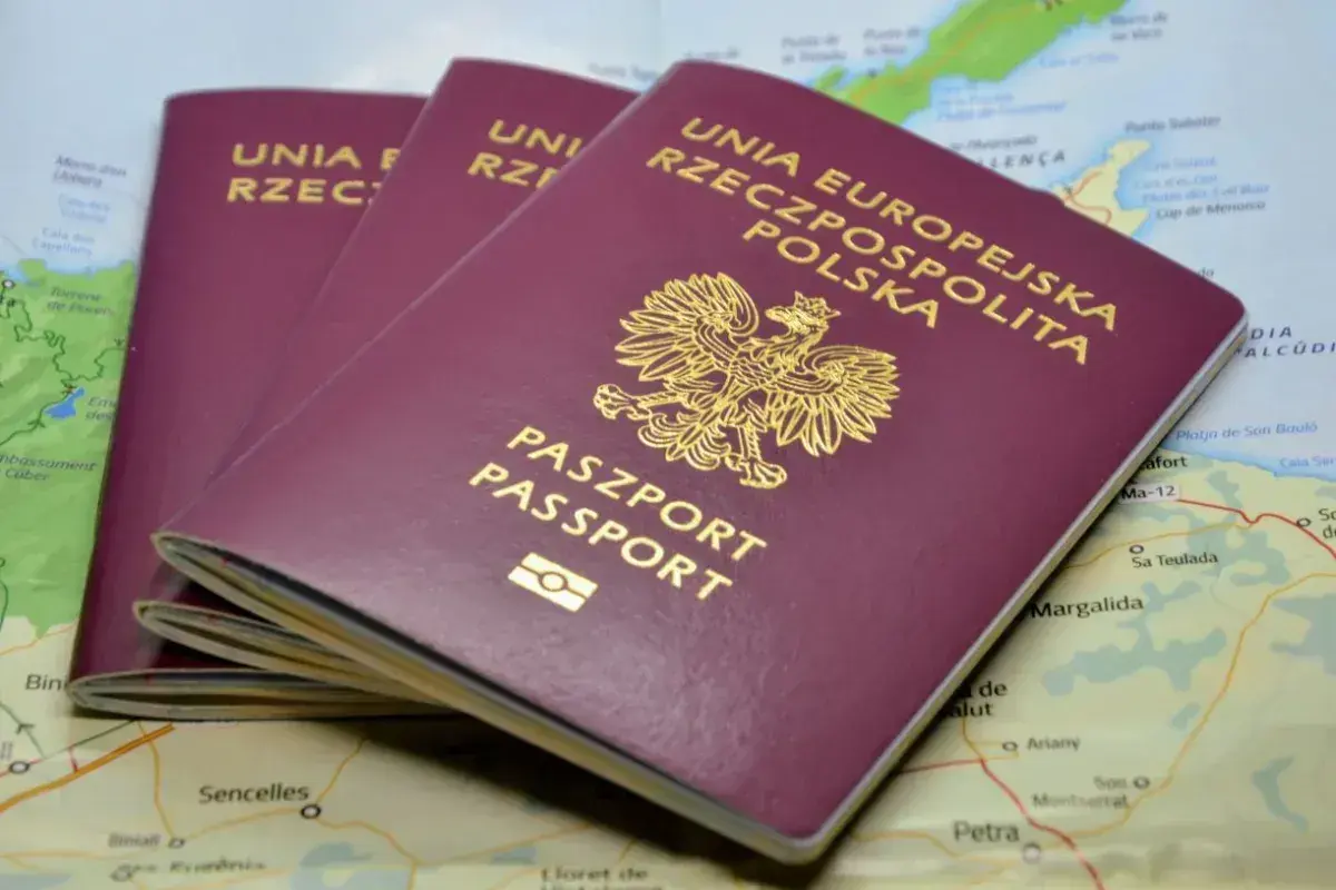 Trzy polskie paszporty leżą na mapie. Zastanawiasz się, ile się czeka na paszport, by wyruszyć w podróż?