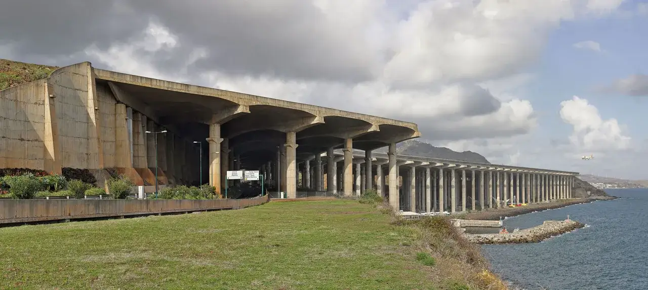 Betonowa konstrukcja nad morzem, część lotniska na Maderze. W oddali widać samolot.