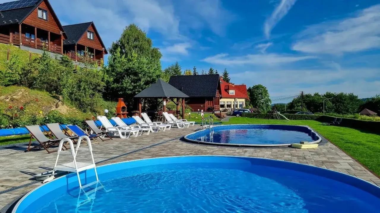 Idealny hotel w Bieszczadach z basenem i leżakami czeka na gości. Słoneczny dzień i błękitna woda zapraszają do relaksu.
