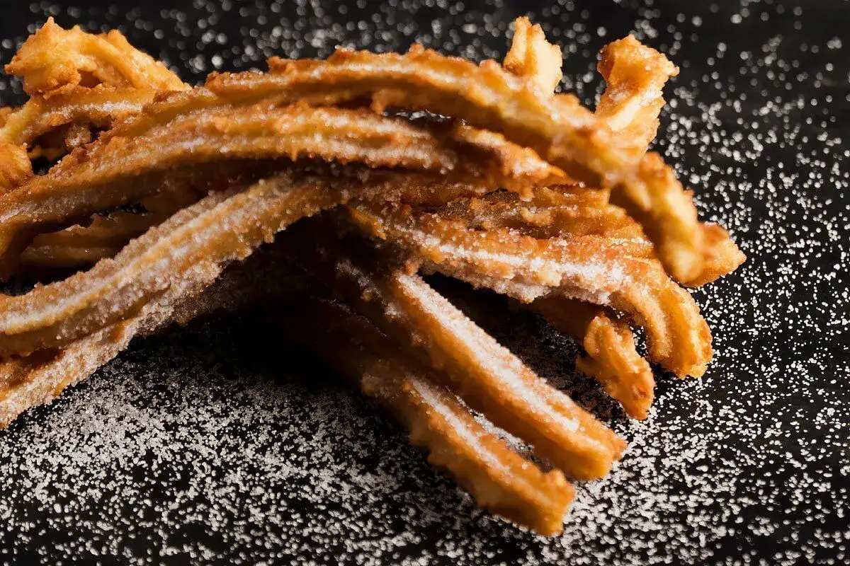 Churros co to? Złociste, chrupiące paluszki smażone na głębokim tłuszczu, posypane cukrem. Idealne do maczania w czekoladzie.